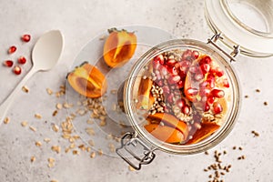 Overnight oatmeal with pomegranate, persimmon and hemp seeds, white background.