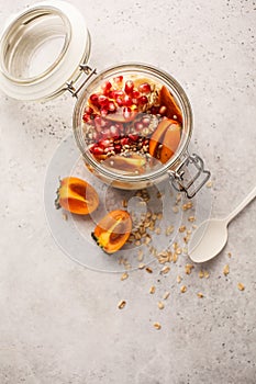 Overnight oatmeal with pomegranate, persimmon and hemp seeds, white background.