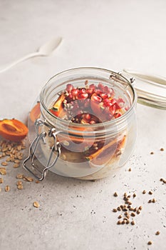 Overnight oatmeal with pomegranate, persimmon and hemp seeds, white background.