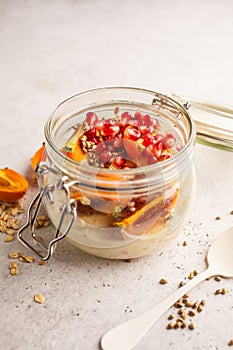 Overnight oatmeal with pomegranate, persimmon and hemp seeds, white background.