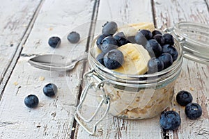 Overnight oats with blueberries and bananas on a white wood background photo