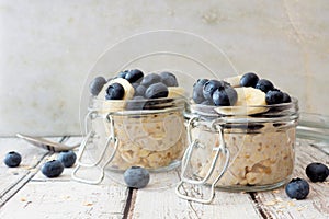 Overnight oats with blueberries and bananas on a white wood background photo