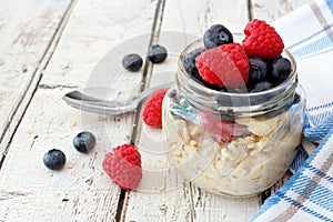 Overnight oats with blueberries and raspberries on a white wood background photo