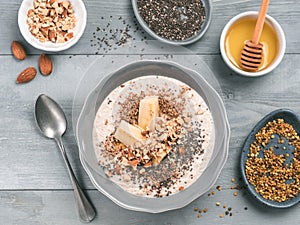 Overnight oats in bowl and ingredients on gray wooden table