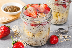 Overnight Oats with Fresh Strawberry, Banana and Chia Seeds in Jars on Light Grey Background, Healthy Snack or Breakfast
