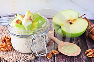 Overnight oats with matcha and green apples in a jar, close up on rustic wood