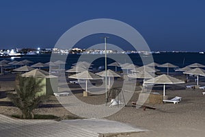 Overnight on the Red Sea beach. Sun umbrellas and empty sunbeds stand in rows