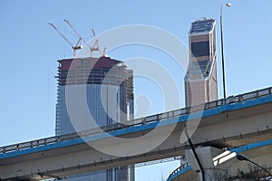 Overpasses on the background of skyscrapers. Blue sky and bright sun. Transport interchanges and urbanism