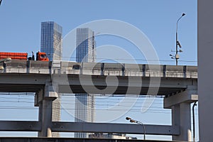 Overpasses on the background of skyscrapers. Blue sky and bright sun. Transport interchanges and urbanism