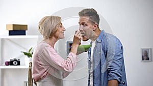 Overprotective mother feeding adult son with spoon, toxic relationship, problem