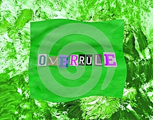 Overrule word from paper magazins letters on green distorted frame and chaotic paint strokes. Grunge textured background