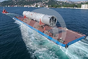 Oversized cargo transportation along the river, a distillation column on a barge floats to factory