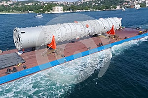 Oversized cargo transportation along the river, a distillation column on a barge floats to factory