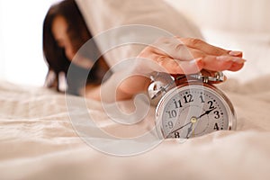 Oversleep woman waking up turning off alarm clock