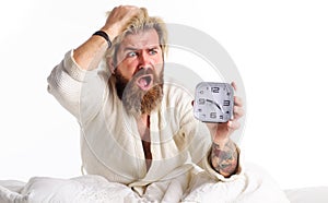 Overslept bearded man with alarm clock in bed. Oversleeping, late for work. Deadline, tardiness.