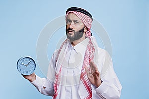 Overslept muslim man holding alarm clock