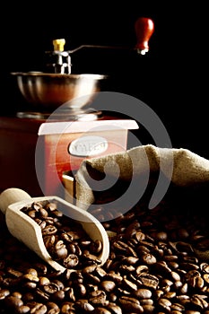 Overturned bag full of coffee beans on black with spatula,mill