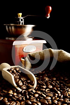 Overturned bag full of coffee beans on black with spatula,mill photo