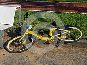 Overturned bike. A yellow bicycle abandoned by a bench. The concept of an accident. Two wheeled vehicle