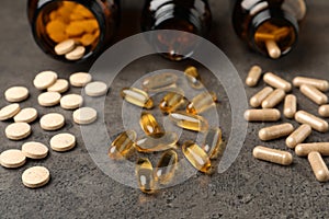 Overturned bottles with different dietary supplements on grey table, closeup