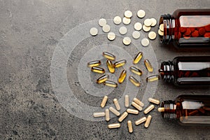 Overturned bottles with different dietary supplements on grey table, flat lay. Space for text