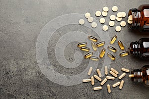 Overturned bottles with different dietary supplements on grey table, flat lay. Space for text