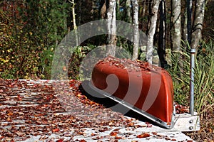 overturned canoe on a dock with fallen leaves in fall
