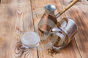 Overturned cezve with coffee beans, bowl with ground coffee on wooden table