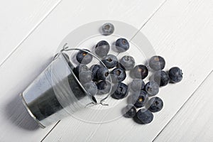 Overturned decorative bucket. Scattered large blueberries. International day without diets. On a white background. Close-up