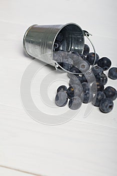 Overturned decorative bucket. Scattered large blueberries. International day without diets. On a white background. Close-up