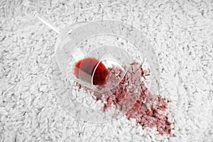 Overturned glass and spilled exquisite red wine on carpet