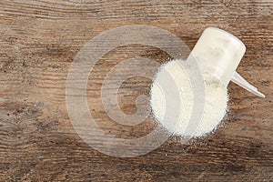 Overturned measuring scoop with protein powder on table, top view. Space for text