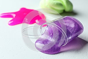 Overturned plastic container with purple slime on white. Space for text