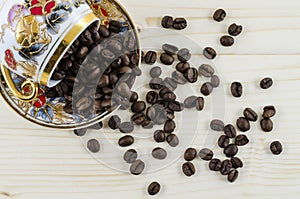 Overturned porcelain coffee cup with coffee beans on wooden table