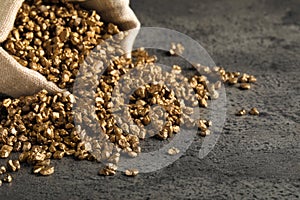 Overturned sack of gold nuggets on grey table