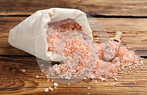 Overturned sack of pink himalayan salt on wooden table