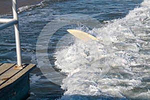 An overturned surf board is seen riding a wave in the ocean with the hand of the surfer who is under the board seen