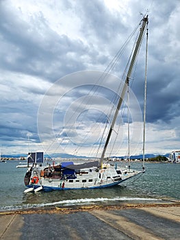 Overturned yacht stranded on the shore of sea beach on cloudy day. Consequences of a storm in resort town