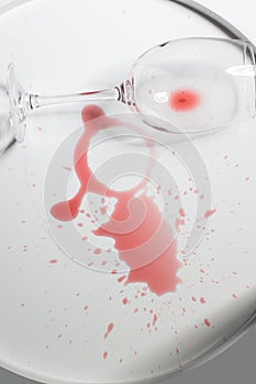 Overturted empty wine glass lies on spilled red wine