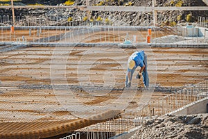 Overview of construction worker using pincers and fixing steel rebar or armature steel at a building site before the concrete is