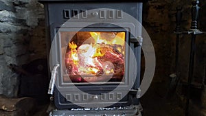Overview of a fire inside a log burning stove with lots of flames and glowing embers