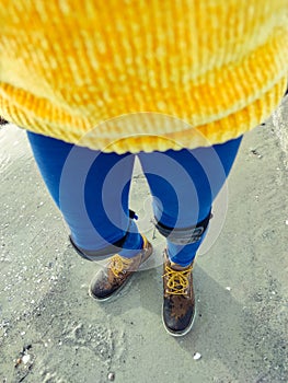 Overview photo of teenager child girls legs standing in modern boots  on sand on Baltic sea beach