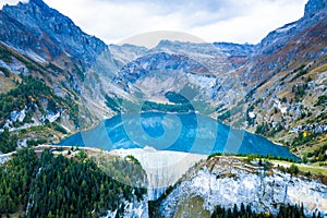 Overview of water dam and reservoir lake in Swiss Alps mountains producing sustainable hydropower, hydroelectricity generation,