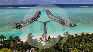 Overwater bungalows at tropical island luxury resort in Maldives. Sunny. Ocean. Sand. Aerial video.