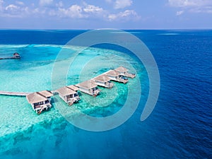 Overwater villas on tropical atoll island for holidays vacation travel and honeymoon. Luxury resort hotel in Maldives or Caribbean