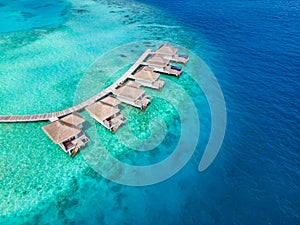 Overwater villas on tropical atoll island for holidays vacation travel and honeymoon. Luxury resort hotel in Maldives or Caribbean