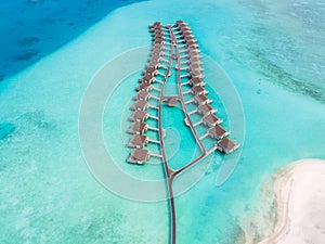 Overwater villas and white sand beach on tropical atoll island for holidays vacation travel and honeymoon. Luxury resort hotel in