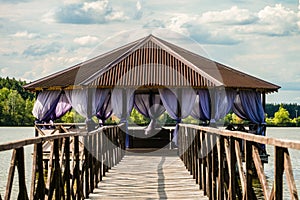 Overwater wooden gazebo on lake. Distance perspective