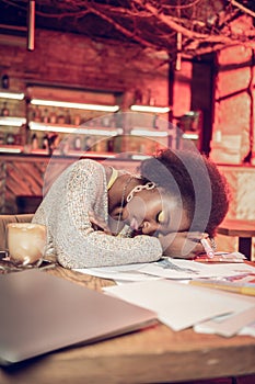 Overweary afro-american fashion creator sleeping over cafeteria table