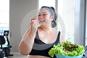 Overweight Asian female happy to eat organic apple for healthy in gym. Weight loss workout, healthy lifestyle concept